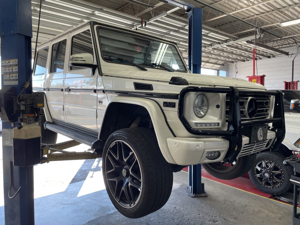 A luxury Mercedes vehicle raised on a digital lift bay for a comprehensive undercarriage inspection.