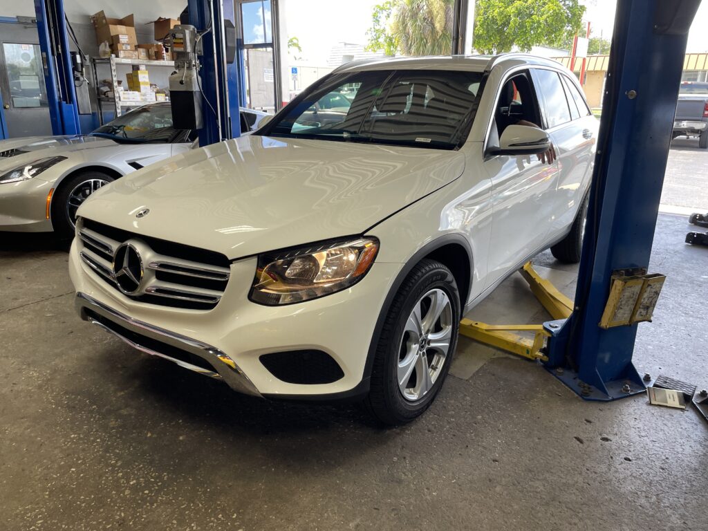 A Mercedes-Benz undergoing a specialized service and component repair inside a clean shop bay.